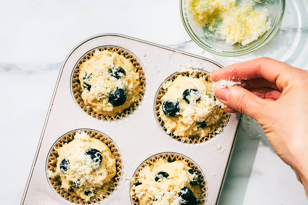 Sprinkling lemon sugar over cottage cheese blueberry muffins before baking.