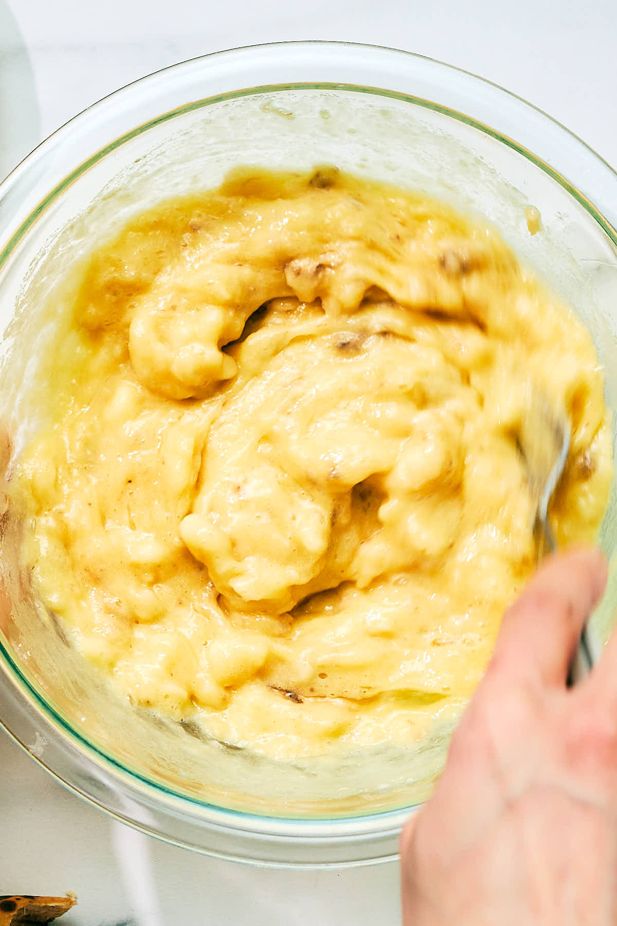 Bananas and eggs being mixed with a fork to ripen before making banana muffins.