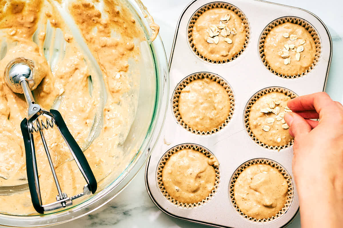 Banana Cottage Cheese Muffins being sprinkled with oats before baking.