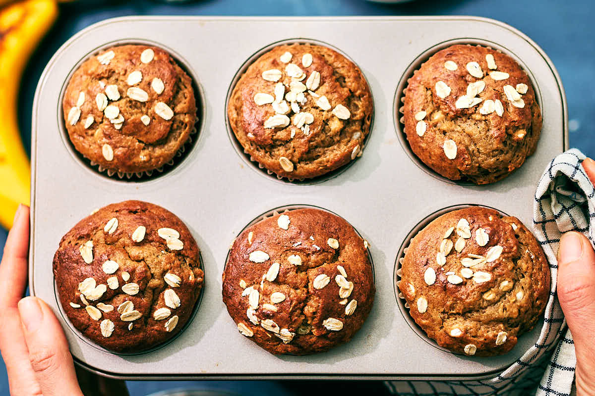 Evergreen Kitchen's Banana Cottage Cheese Muffins topped with oats in a muffin tin.