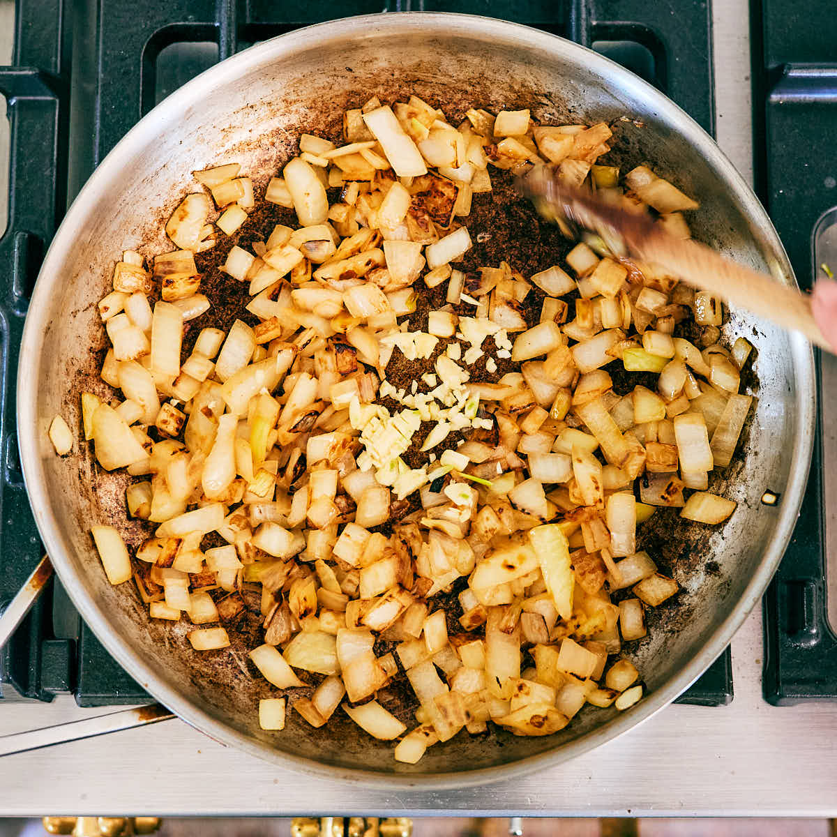 Onion and garlic being sauteed in a skillet.