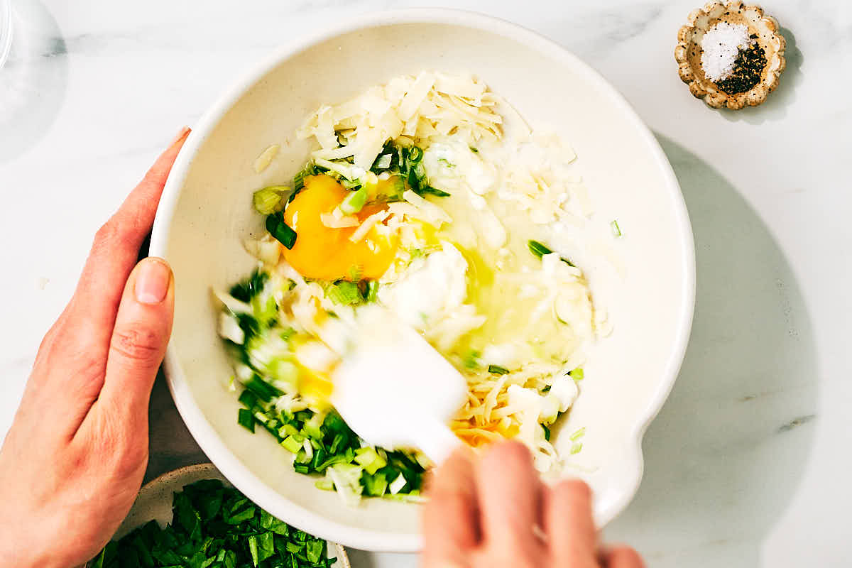 Ingredients being mixed together in a bowl for high protein cottage cheese waffles.