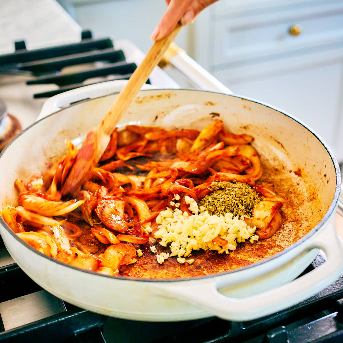 Onion, tomato paste, garlic, oregano being sauteed in a skillet.
