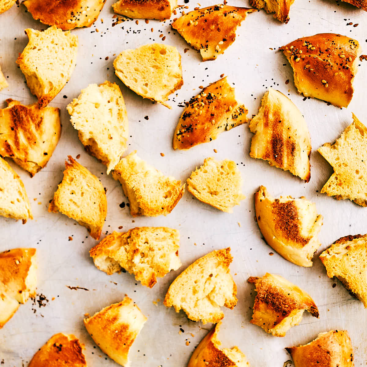 Oven toasted bagel pieces on a baking sheet.