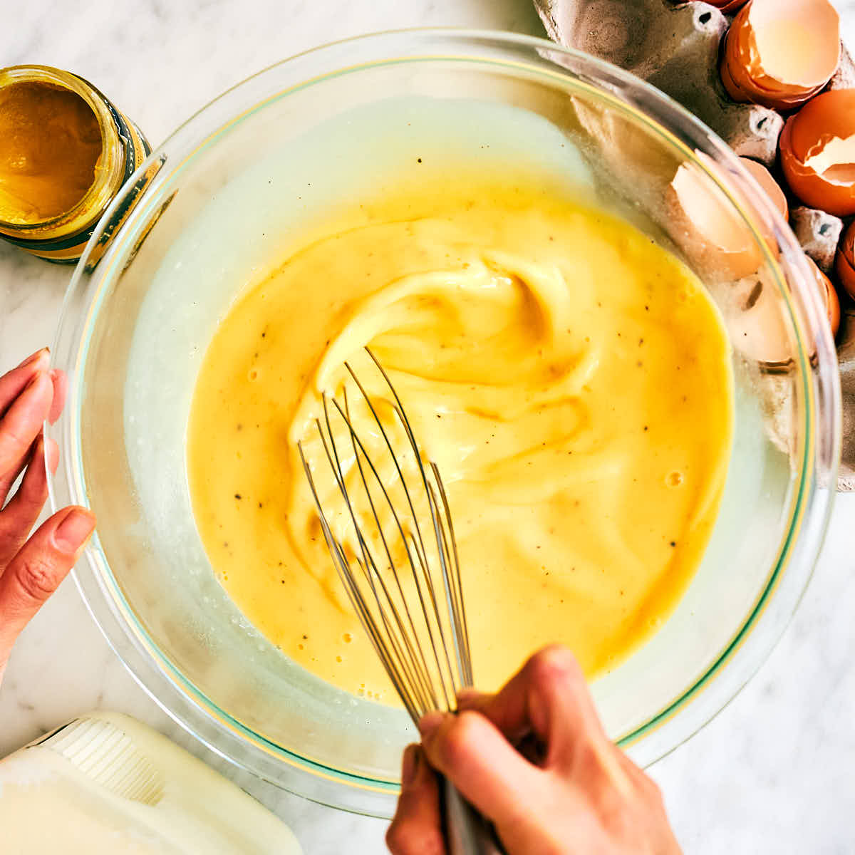 Eggs, milk, seasonings being whisked in a bowl for breakfast casserole.