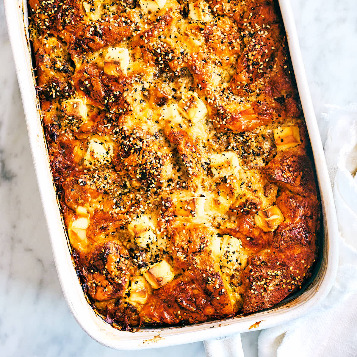 Freshly baked vegetarian Bagel Breakfast Casserole topped with cream cheese.