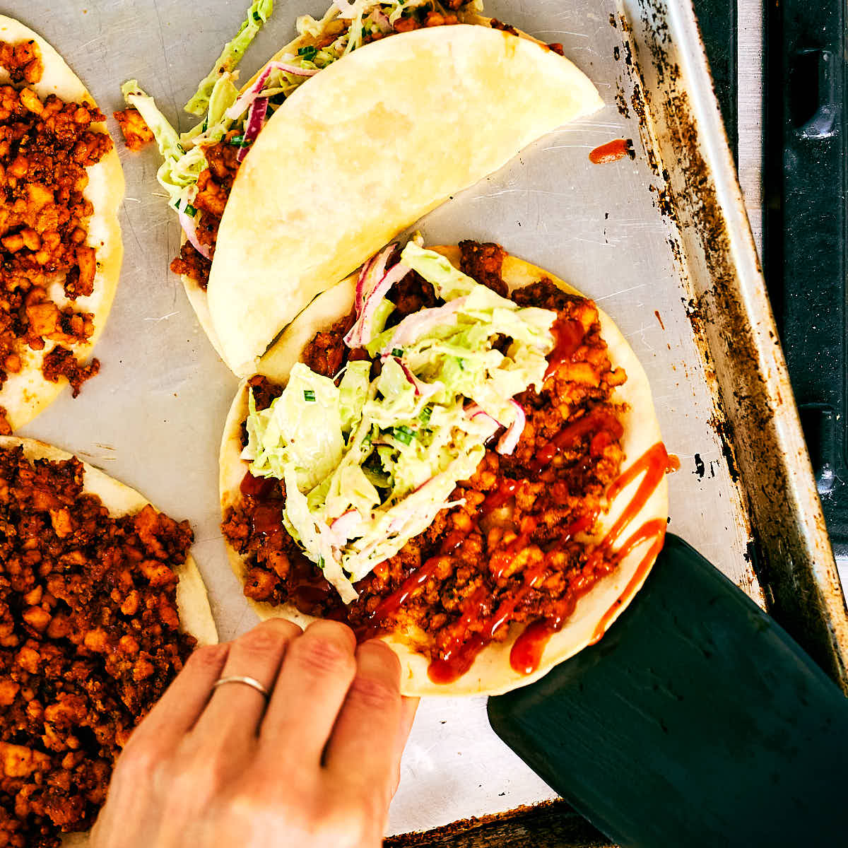 Evergreen Kitchen's Crispy Sheet Pan Tacos with Barbecue sauce tofu being assembled.