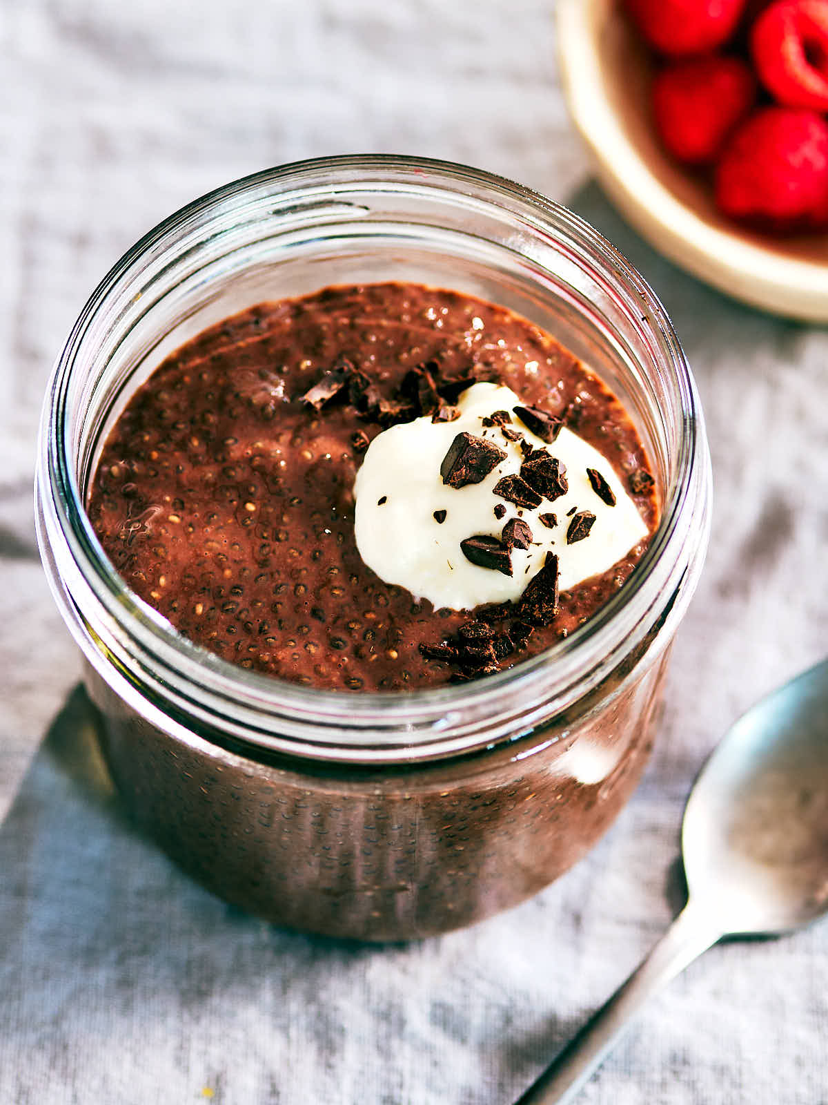 High Protein Chocolate Chia Pudding in a glass jar topped with yogurt and chopped chocolate.