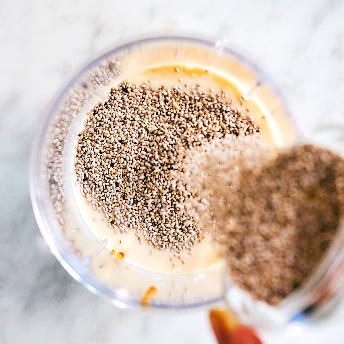 Chia seeds being added to a blender for blended chia pudding.