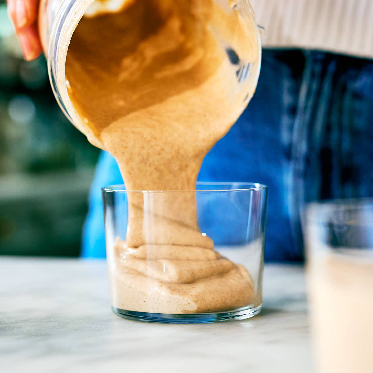 Blended peanut butter chia pudding being poured into individual cups.