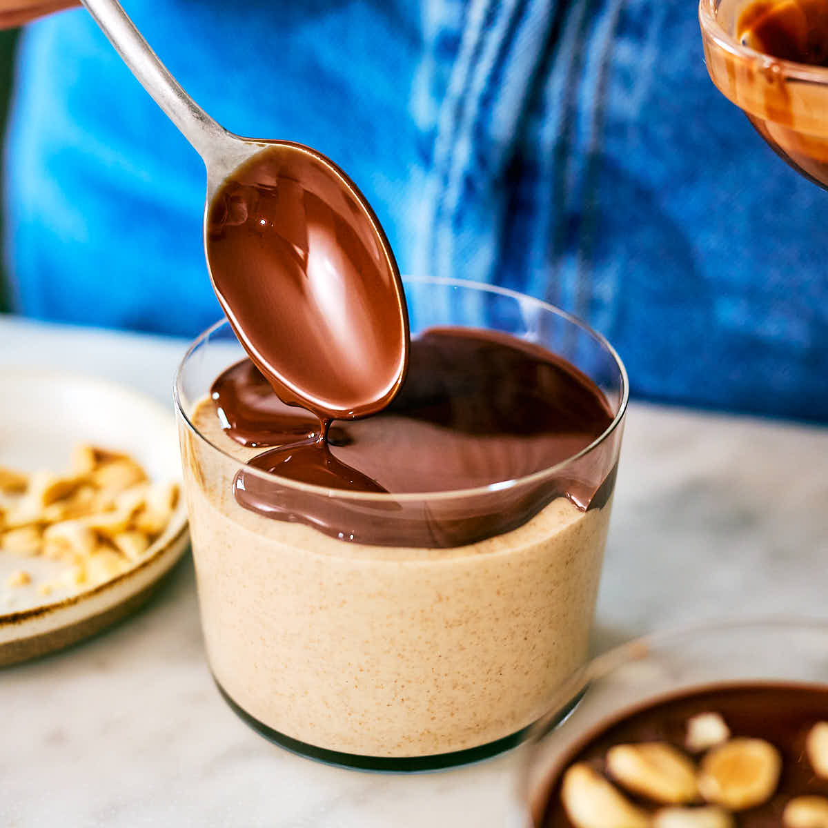 Melted chocolate being spooned on top of peanut butter chia pudding.