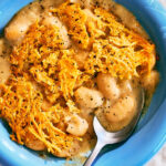 Cacio e Pepe Beans with a Parmesan Crisp in a bowl with a spoon.