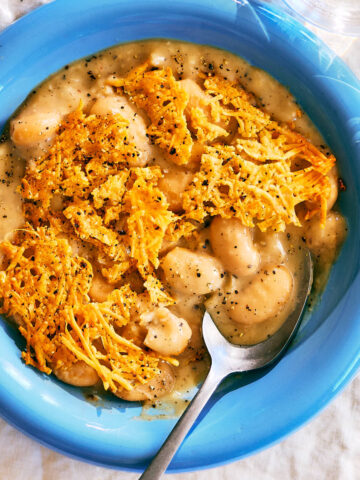 Cacio e Pepe Beans with a Parmesan Crisp in a bowl with a spoon.