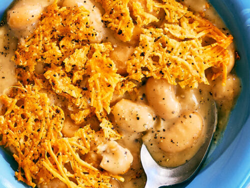 Cacio e Pepe Beans with a Parmesan Crisp in a bowl with a spoon.