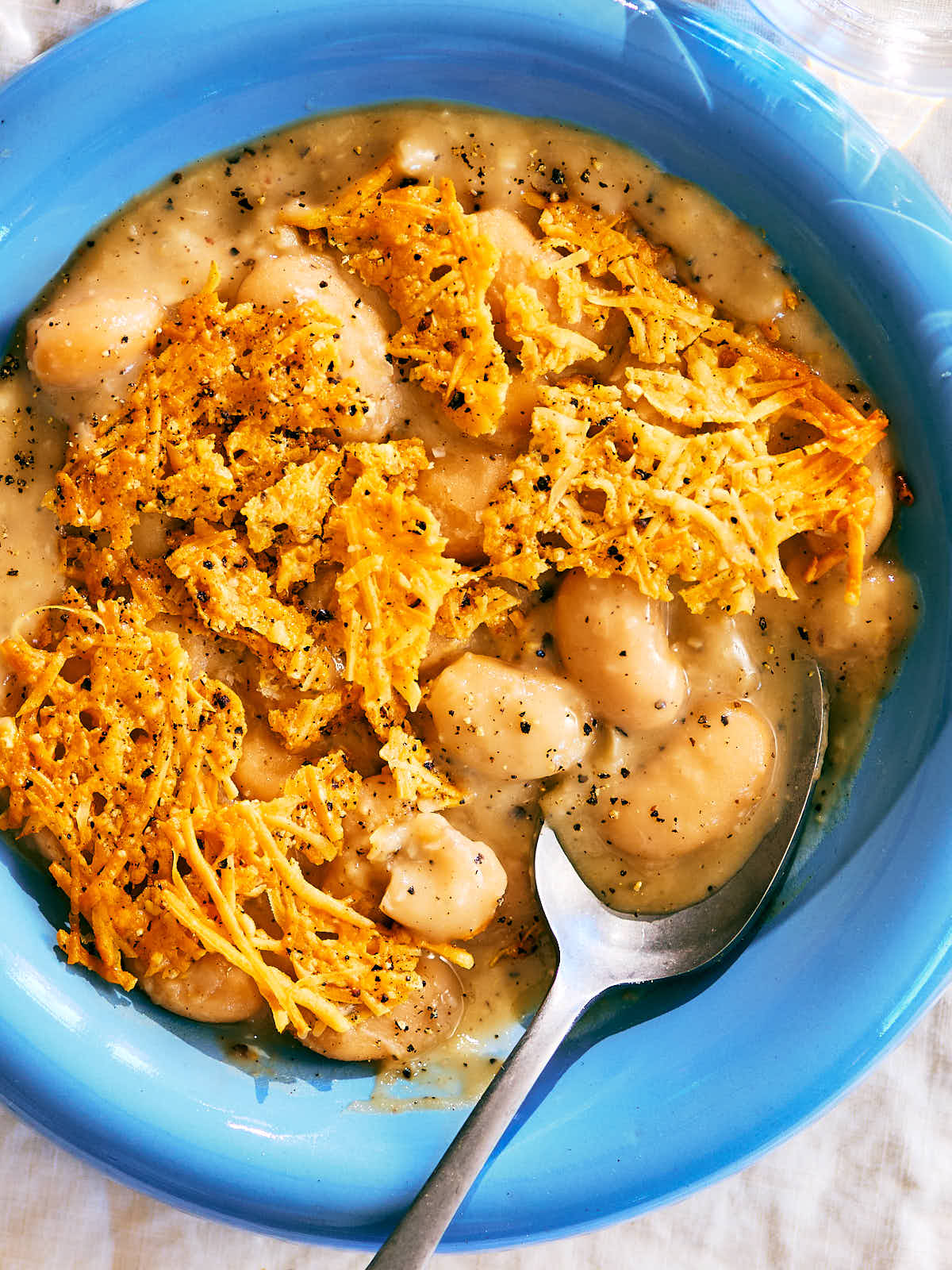 Cacio e Pepe Beans with a Parmesan Crisp in a bowl with a spoon.