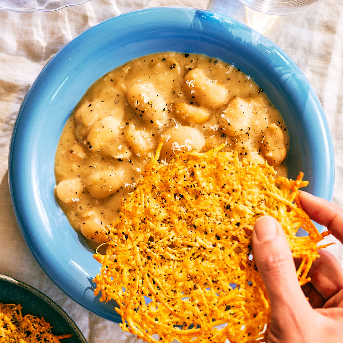 Topping Evergreen Kitchen's Cacio e Pepe Butter Beans with a parmesan crisp.