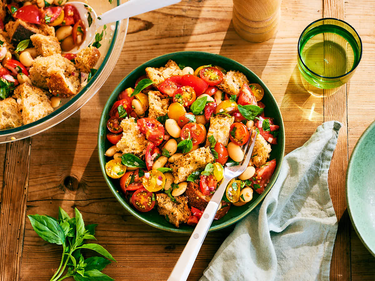Evergreen Kitchen's Tomato Panzanella Salad with beans in bowls on a wood table.
