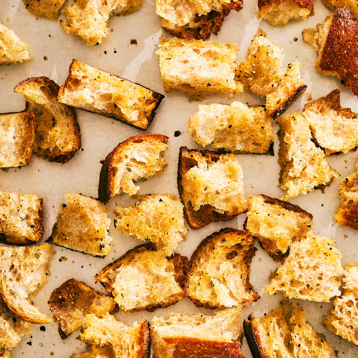 Bread being toasted on a baking sheet for panzanella salad.