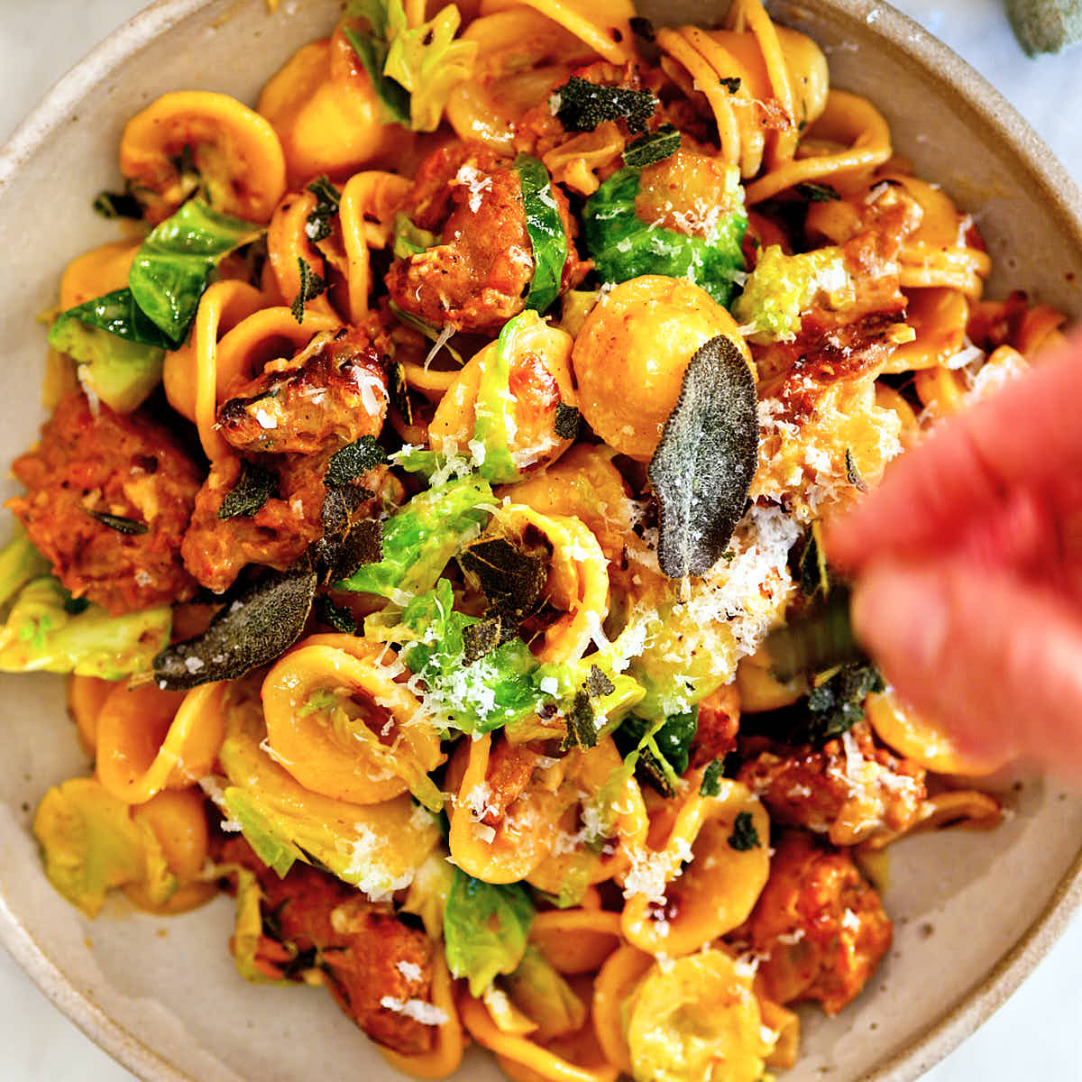 Parmesan cheese being sprinkled over vegetarian Brussels sprouts pasta.