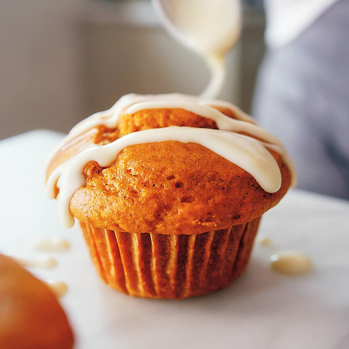 Drizzling high protein pumpkin muffins with cream cheese icing.