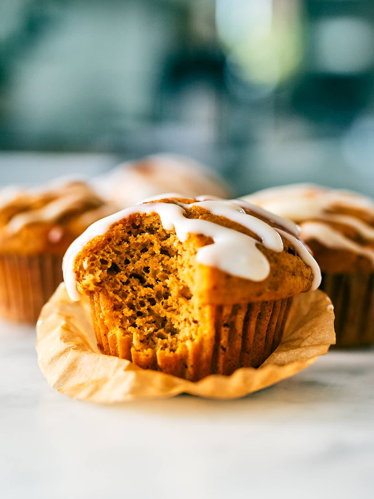 Pumpkin Protein Muffin topped with cream cheese icing on a kitchen counter.