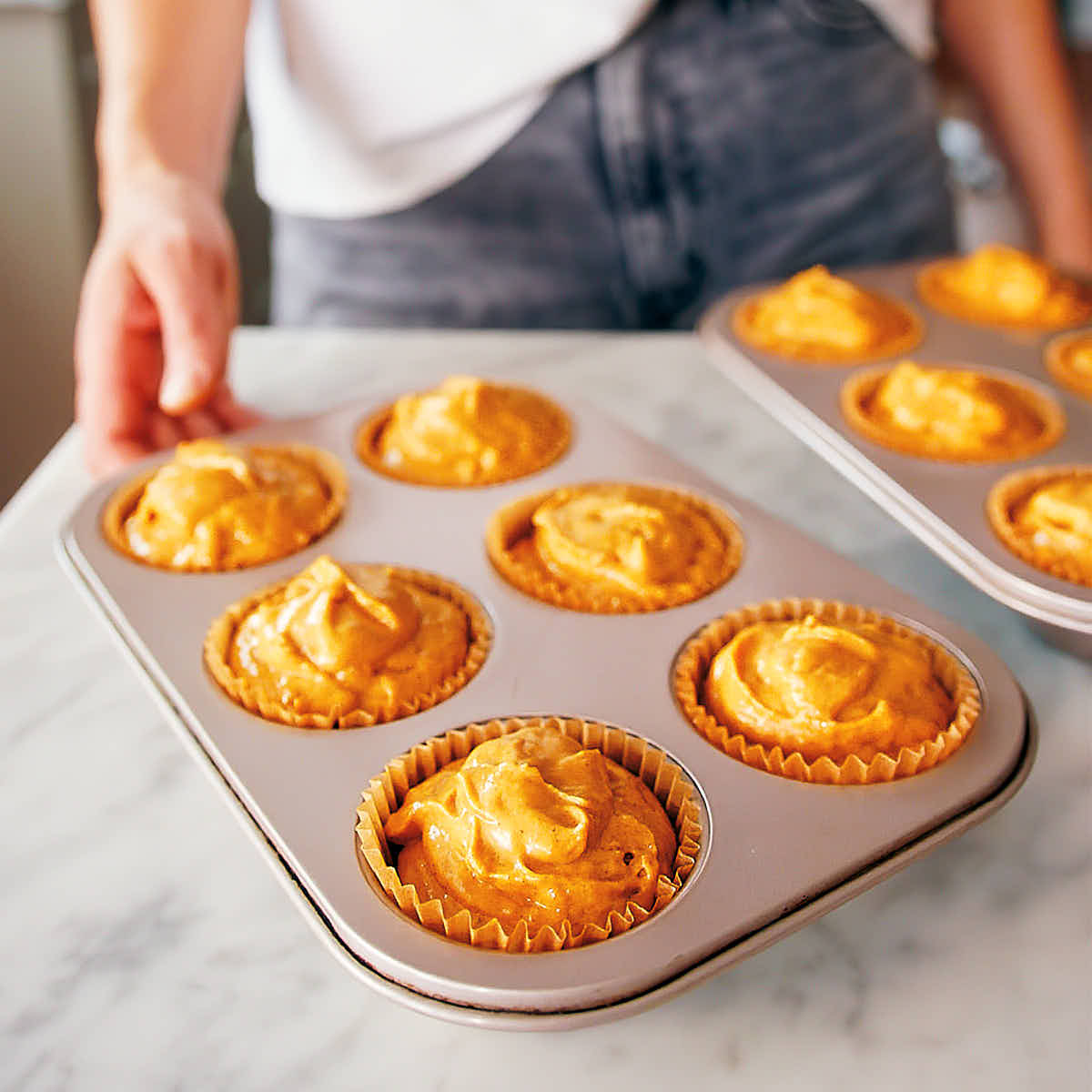 Pumpkin protein muffin batter scooped into muffin tins before baking.